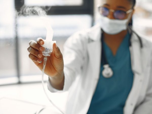 Profissional de saúde segura um nebulizador em um ambiente clínico.