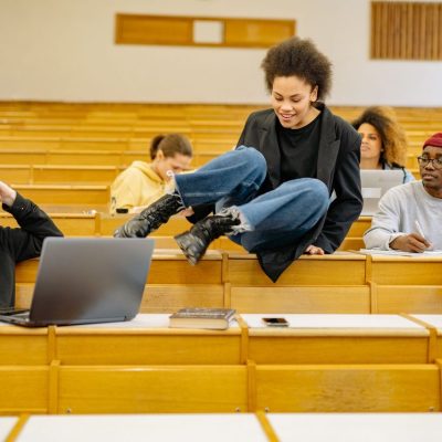 Estudantes universitários de diferentes perfis interagem e estudam em uma sala de aula.