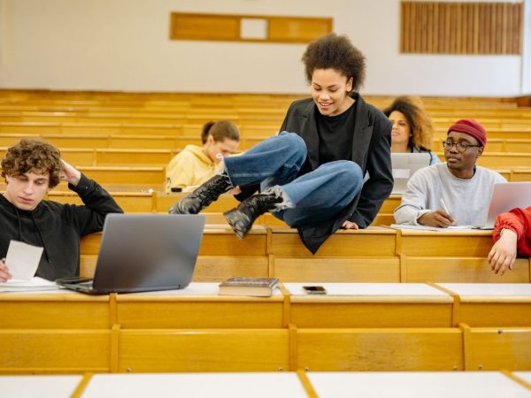 Estudantes universitários de diferentes perfis interagem e estudam em uma sala de aula.