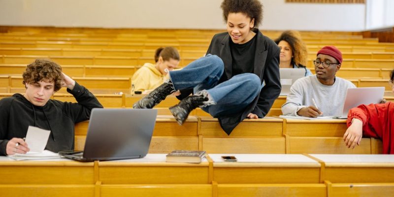 Estudantes universitários de diferentes perfis interagem e estudam em uma sala de aula.